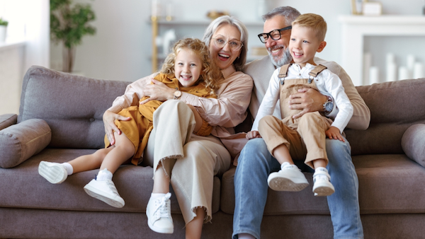 Grandparents hugging grandchildren on grey couch