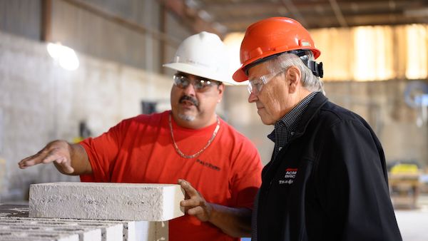 Dennis Knautz in a hard hat speaking with an employee