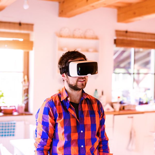 Man wearing virtual reality goggles standing in a kitchen